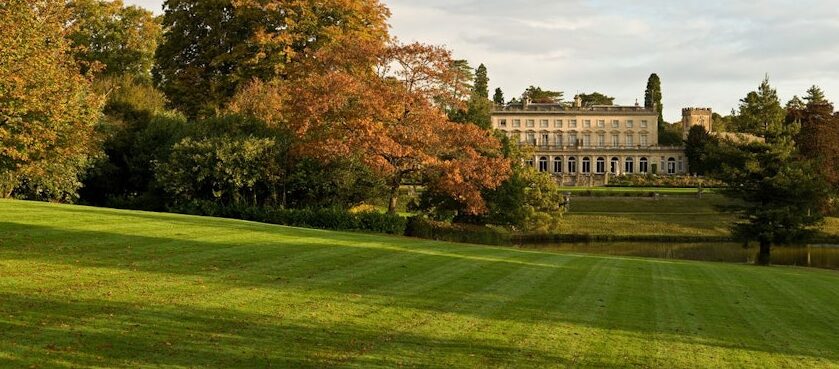 A large mansion behind a field and trees