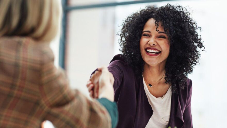 Receptionist smiles in her interview and shakes hands with her interviewer