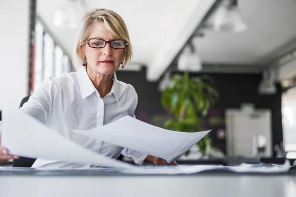 A recruiter looks over papers in a sunsoaked office at a desk.