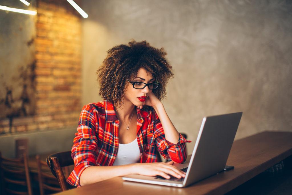 Young woman sitting at cafe working on laptop