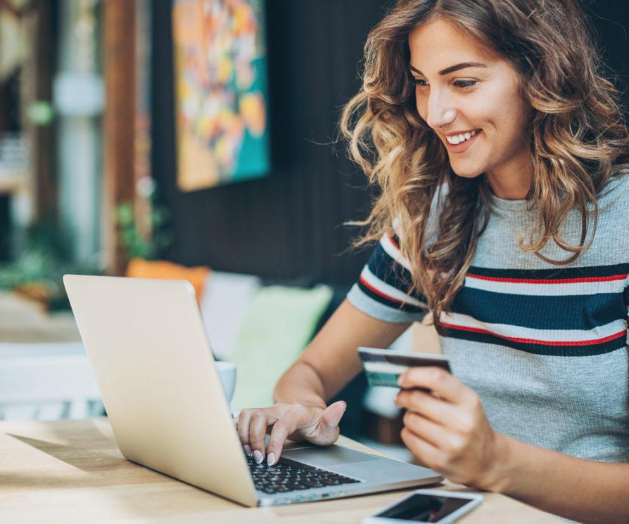 A Private PA is holding a credit card and typing on a laptop.