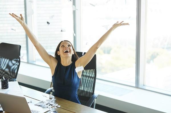 A young woman in an office wearing businesswear who is happy to resign from her role.