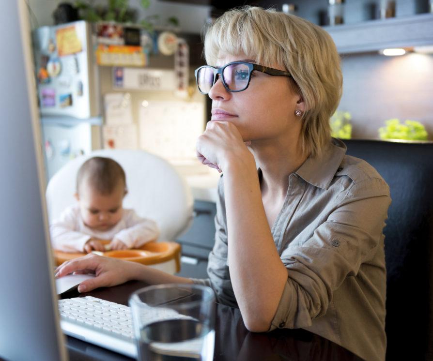 Mum working at home with a baby in the background