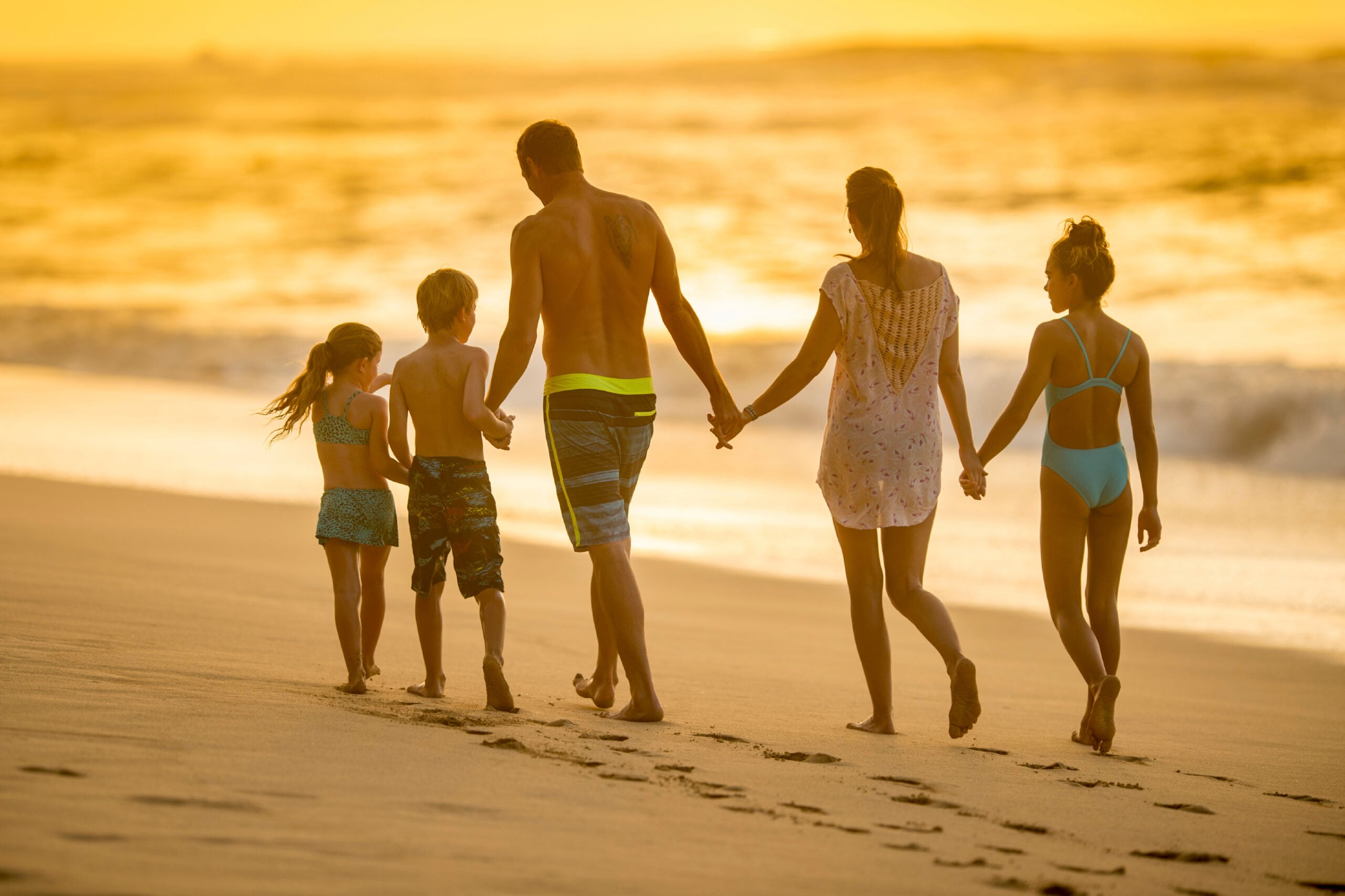 A family of five walking together down the beach