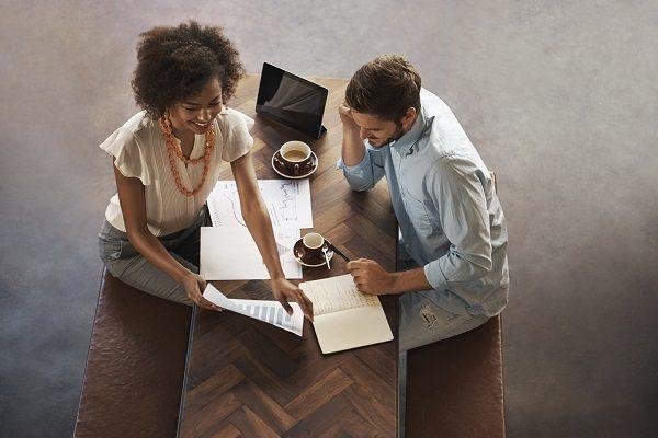 An overhead shot of two colleagues having a business meeting in a hip, open plan office.
