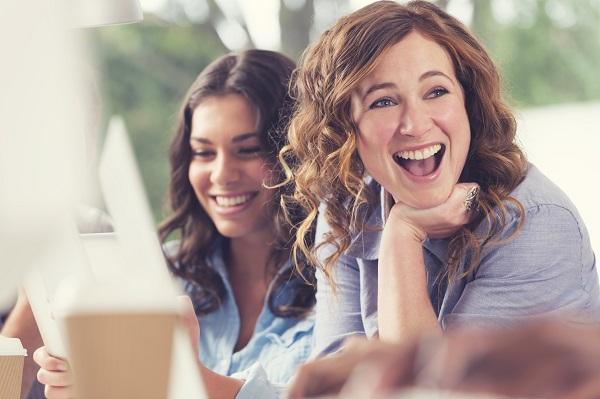 Two smiling women in business wear in an office meeting room.