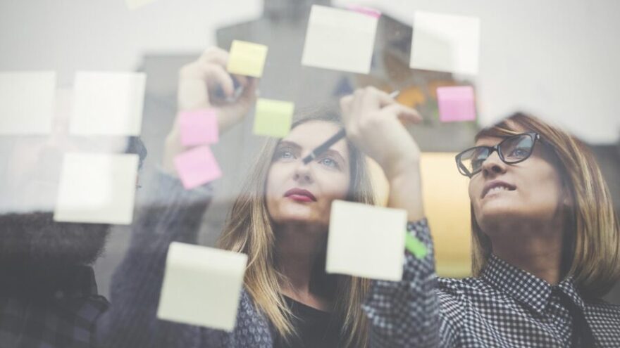 Two women creative brainstorm while writing out post it notes