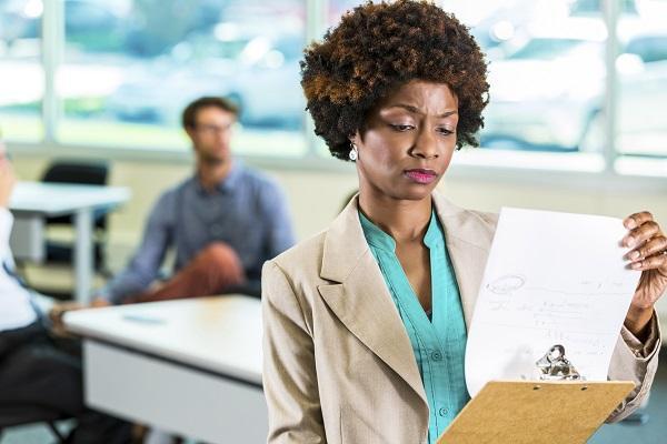 A business woman holding a clipboard and looking disappointed after an unsuccessful interview.