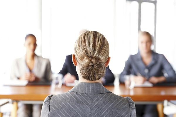 A woman sitting at a panel interview, presenting herself professionally in business wear.
