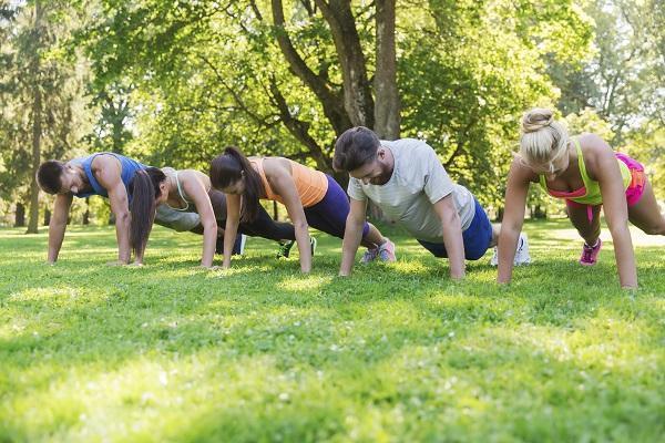 Five people exercising in the park together during work.