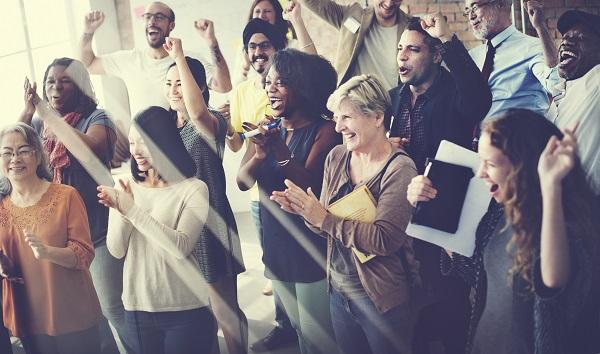A group of people cheering, clapping, laughing and smiling in an office.