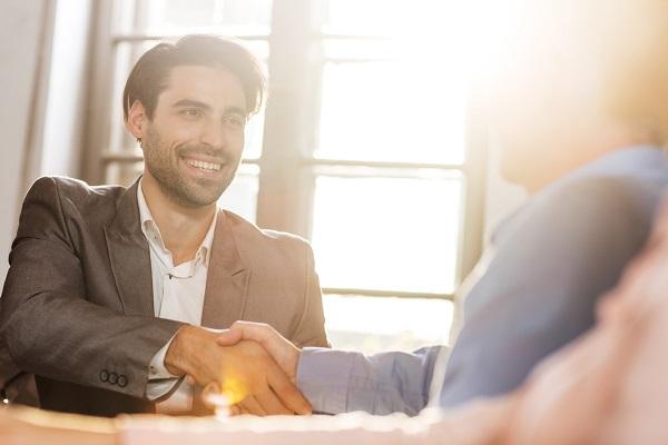 A chosen candidate shaking hands with an employer in a sunlit office.