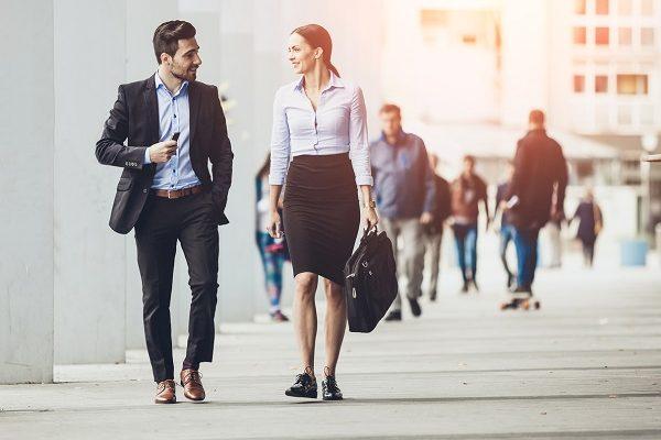 A business man and woman who work in the City of London walking around and talking to each other.