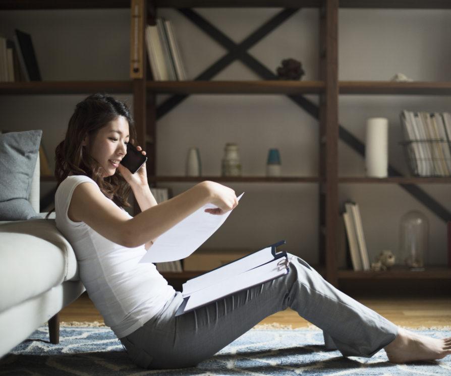 Young woman talking on the smartphone while watching the documents.