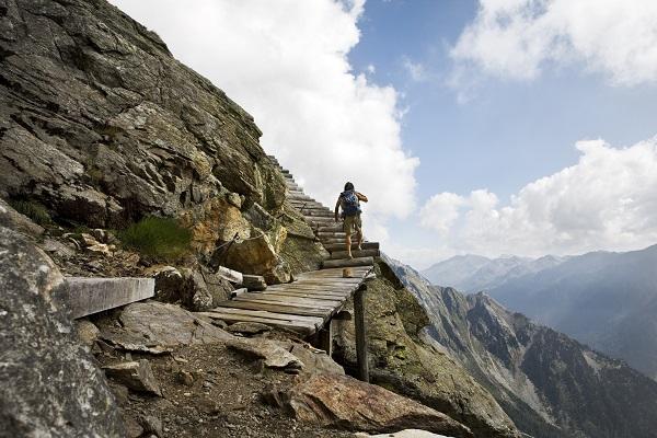 An adventurer climbing a trail of logs on the way up a mountain in the sky.