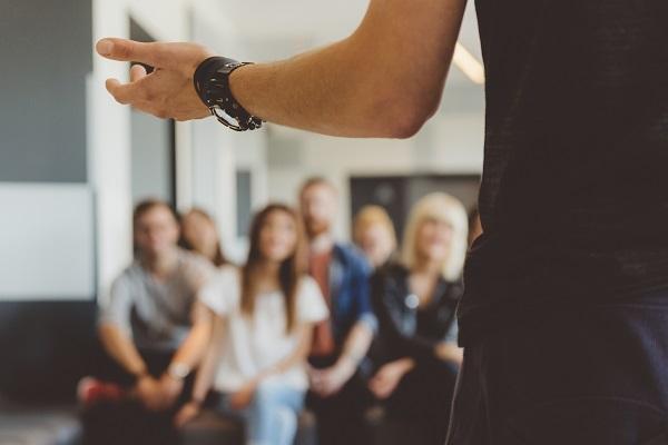 A man presenting a workshop in front of a group of colleagues, talking to his talent pool.