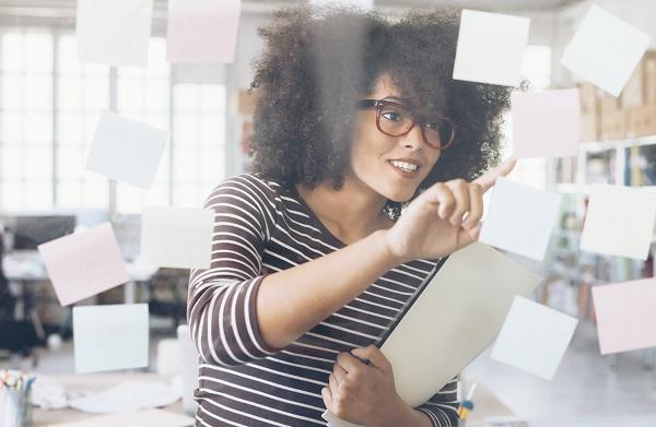 Portrait of businesswoman in a modern office. She's wearing eyeglasses and reading sticky notes