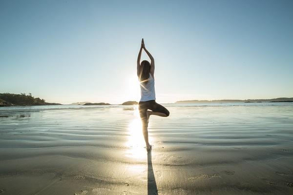 A private PA practicing yoga on a beach at sunset.