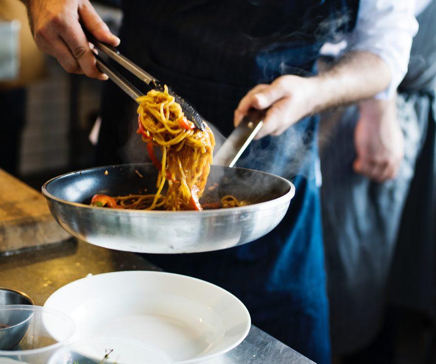 chef cooking pasta in pan