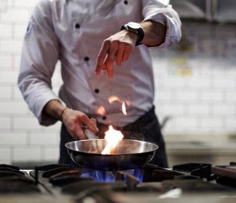 A chef cooks in a kitchen. He gently fries the vegetables while cooking the dish.