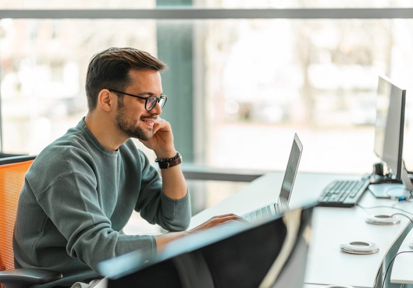 A digital professional working on a laptop in an office.