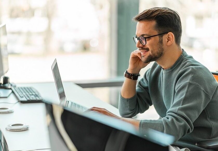 A digital professional working on a laptop in an office.