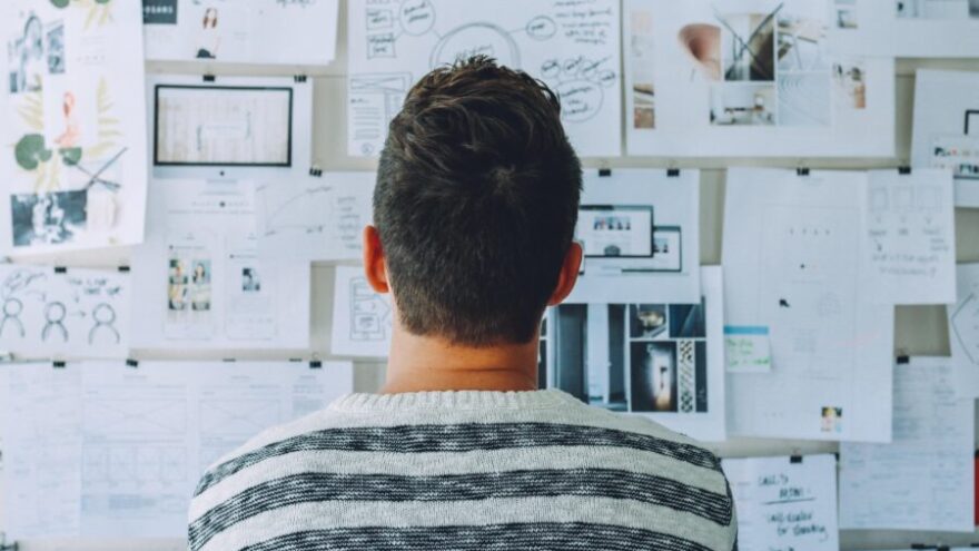 Shot of the back of a man's head in front of a creative board