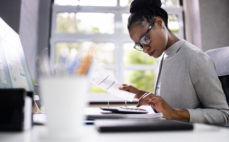 Woman updating document with a calculator