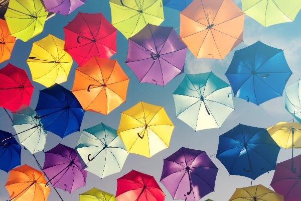 A shot of several colourful umbrellas in the sky, symbolising diversity hiring.