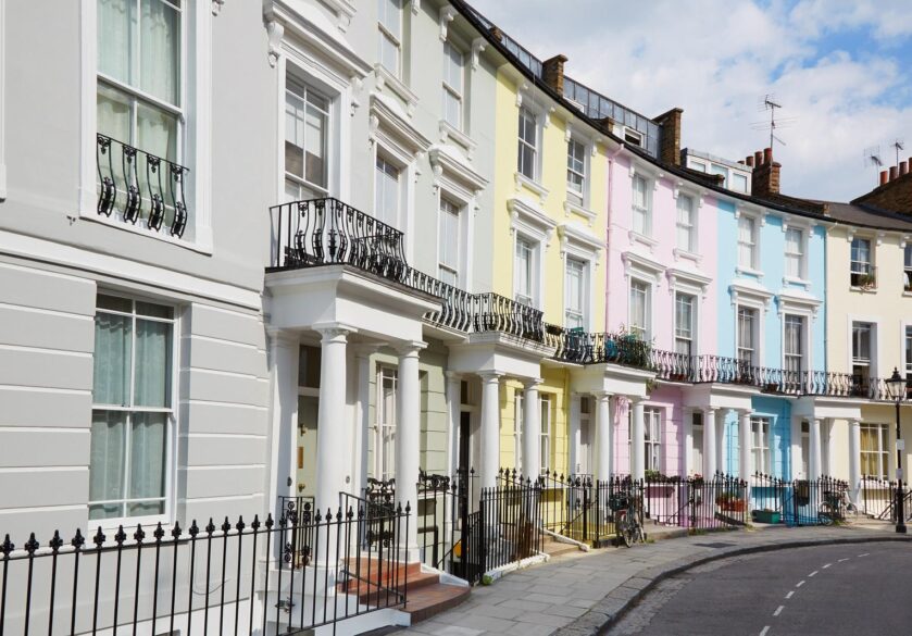 Colourful private London houses in Primrose hill lined up. They are painted grey, yellow, pink, blue and beige.