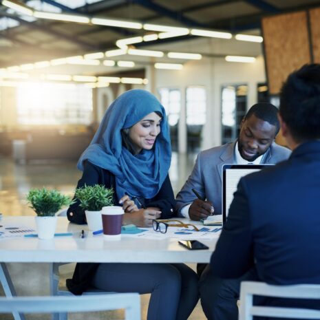 One female and two male human resources professionals smile and have a meeting in a modern, bright and contemporary office.