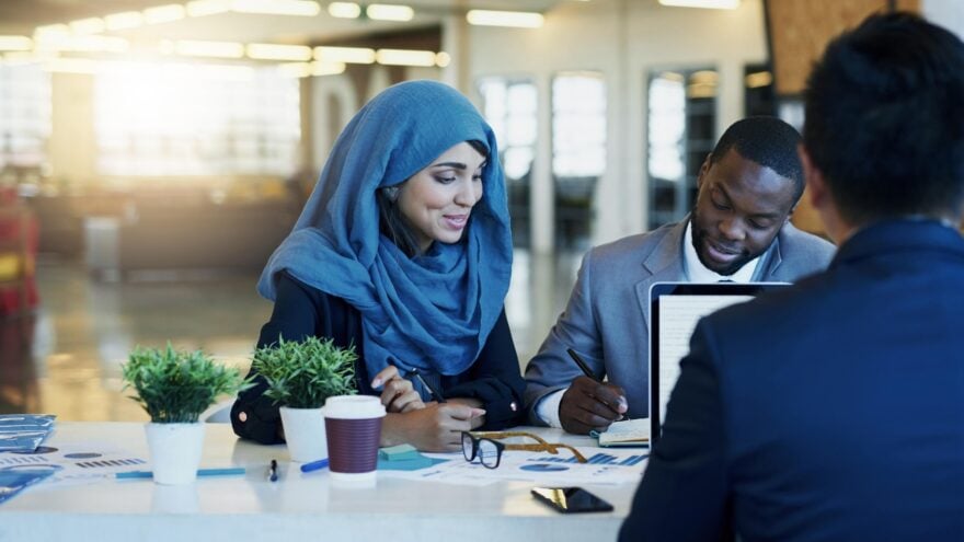 One female and two male human resources professionals smile and have a meeting in a modern, bright and contemporary office.