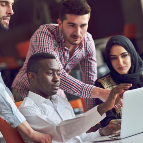 Four workers in Dubai looking at a computer screen