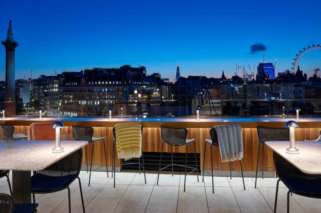 Sunset picture of the rooftop bar with tables and chairs lit from below