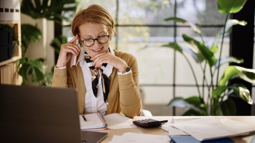 Woman sitting at desk in front of a computer on a phone call