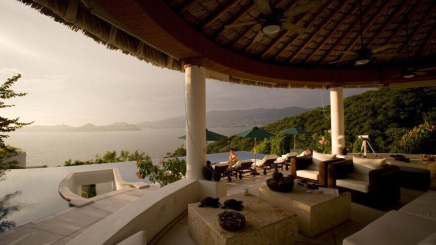 An open air villa with an infinity pool and a view looking out to the ocean during sunset in Acapulco Mexico.