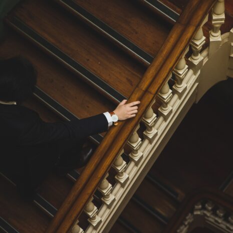 Suited man with watch walking up stairs inside home
