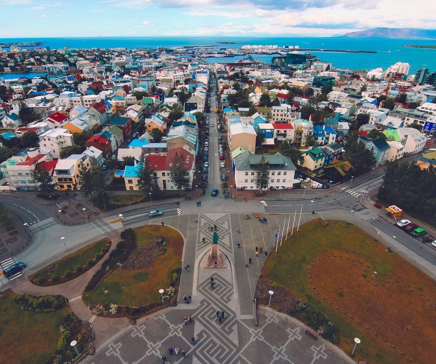 An overhead shot of Iceland’s city centre, near the coast with the sea in the background and colourful houses.