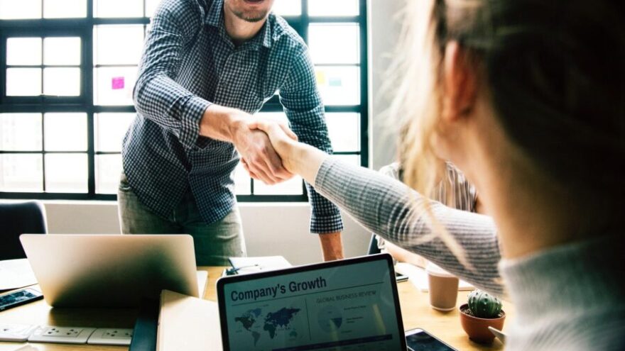 Man and woman shaking hands over a table