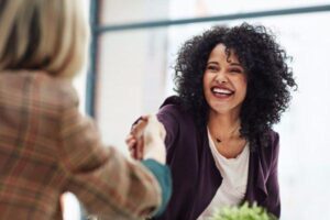 Woman shaking hands with another woman while being interviewed