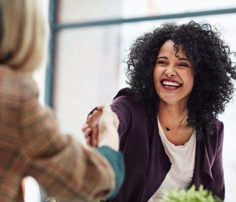 Woman shaking hands with another woman while being interviewed