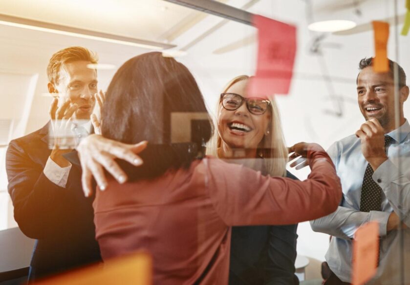 Businesswomen hugging while brainstorming with their team in an office