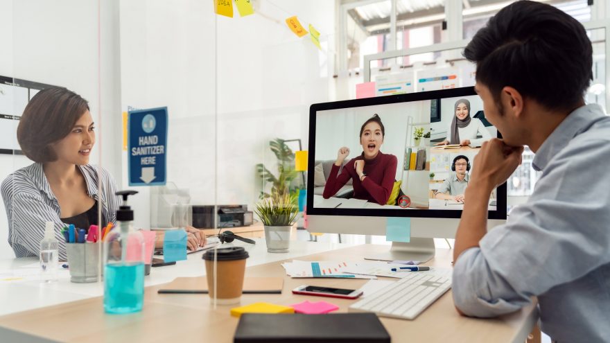 A photo of two business people working together, in conversation with a colleague virtually