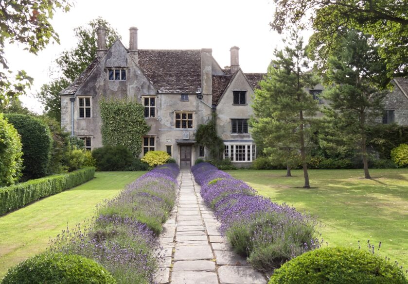 An old stately house with mature grounds on a summers day in the English countryside.
