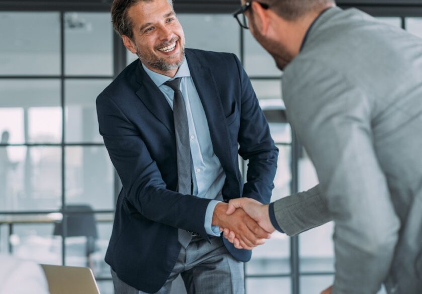 man in suit shaking hand over table