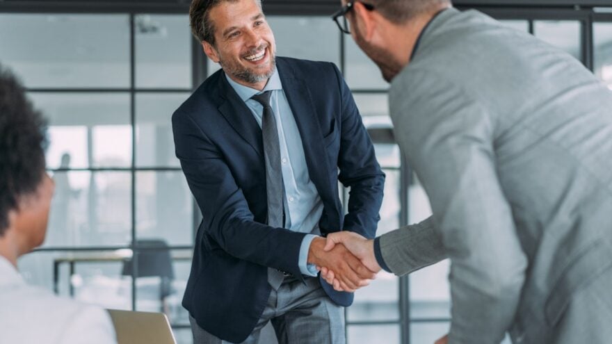 man in suit shaking hand over table