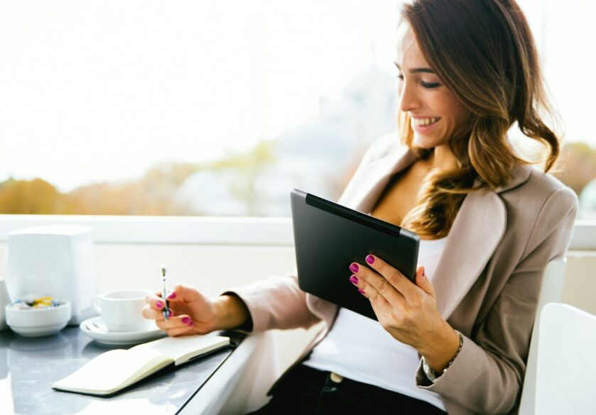 Professional woman looks at ipad and notes