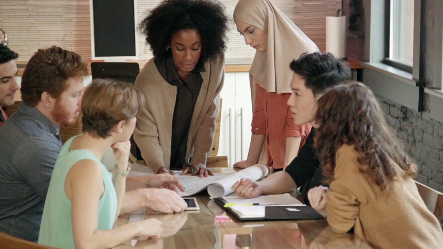 Medium close up of a young woman leading a team meeting.