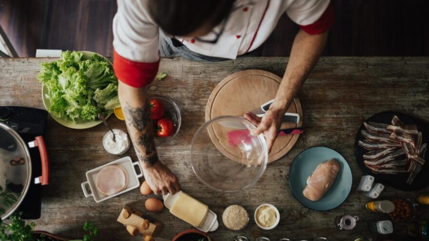 Top view at chef who starts to prepare a meal for dinner with many ingredients around her on the bench