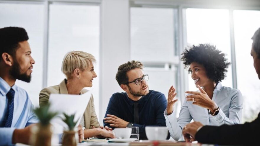A group of managers sitting around a desk, discussing how employee engagement is shifting in 2019.